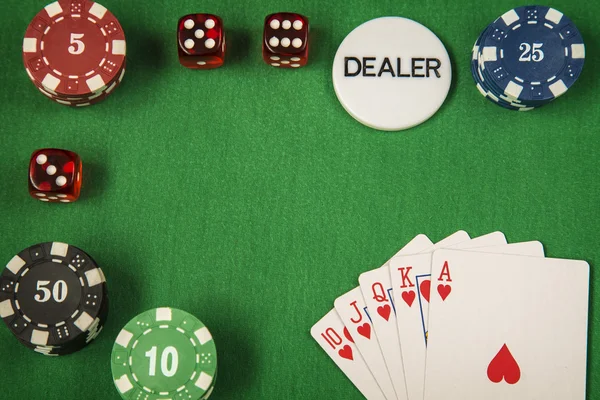Gambling chips, red dice and card for poker on green felt background