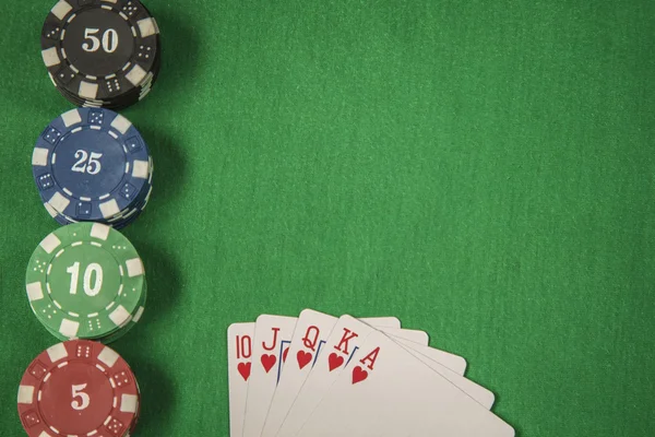 Gambling chips and card for poker on green felt background