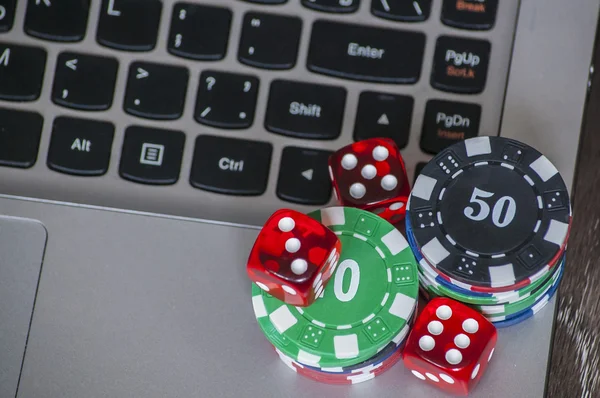 Gambling chips and red dice on laptop keyboard background