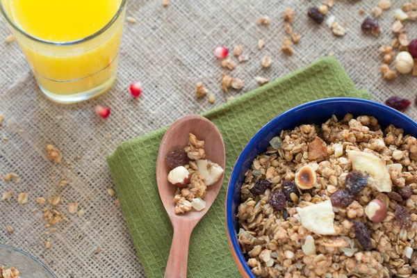 Breakfast bowl of  dry muesli and red berries with wooden spoon on green kitchen towel