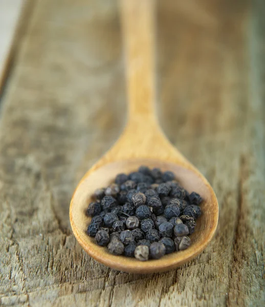 Peppercorn in spoon on white background