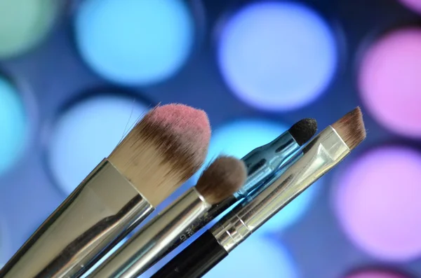 Brushes for make-up on a background palette with eyeshadow