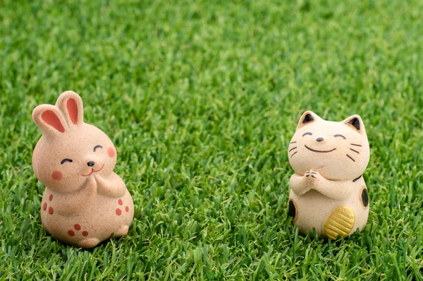 Happy rabbit and lucky cat praying on the grass