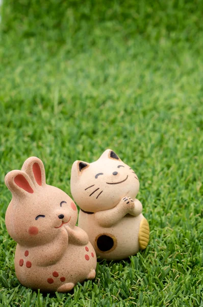 Happy rabbit and lucky cat praying on the grass left