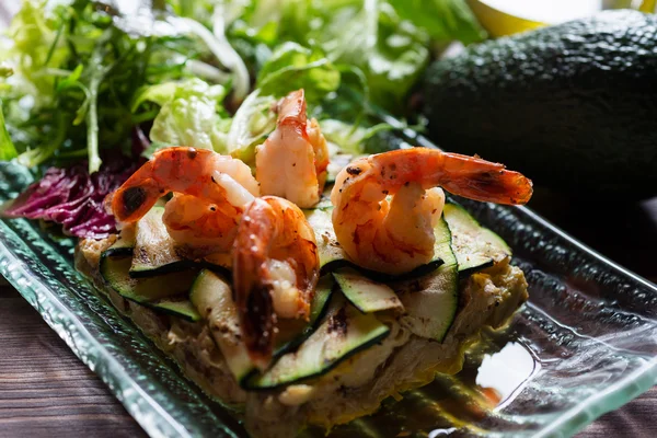 Fresh healthy salad with shrimps and vegetables serving on the plate on a wooden table in a restaurant with decor