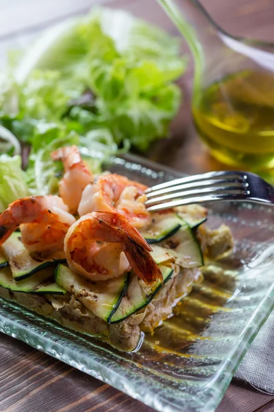 Fresh healthy salad with shrimps and vegetables serving on the plate on a wooden table in a restaurant with decor