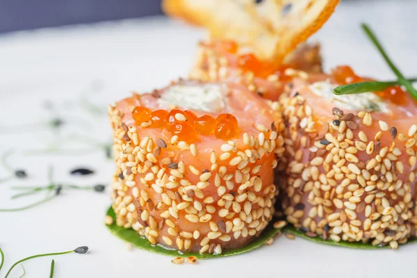 Traditional japanese rolls with salmon and philadelphia cheese, sesame and red caviar on a white plate with decor