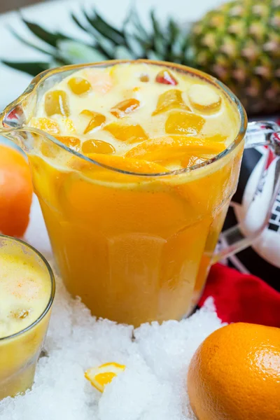 A decanter of bright summer cool refreshing orange lemonade on a table with a creative composition with ice, oranges and fresh mint, soft focus