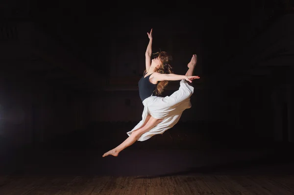 Young brunette dancer girl in split jump