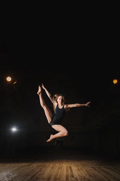 Young brunette dancer girl in split jump