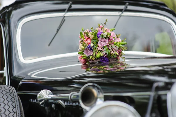 Bouquet of flowers on hood retro wedding car