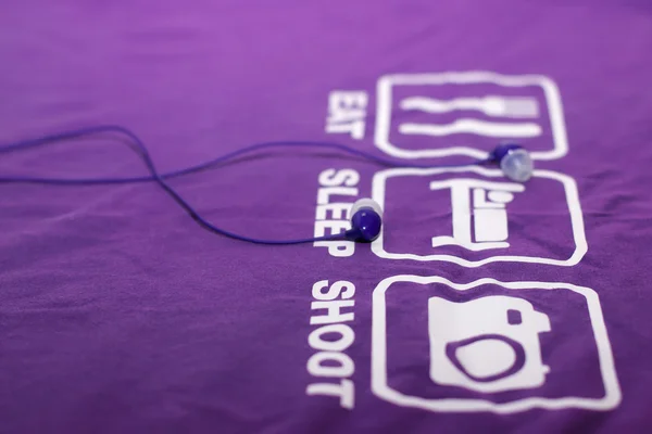 Vacuum blue headphones lying on purple T-shirt