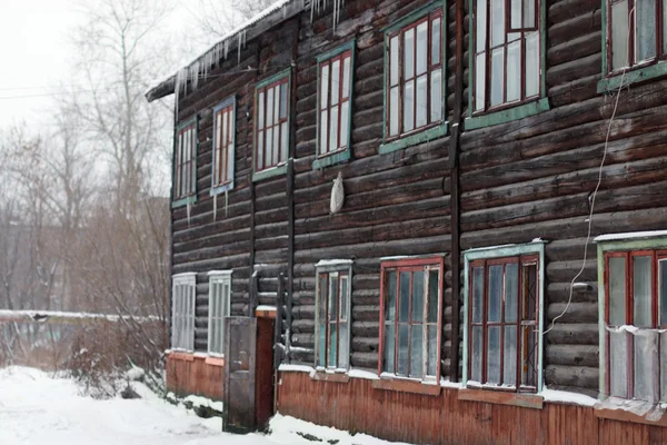 Two-storey wooden house made of logs during snowfall