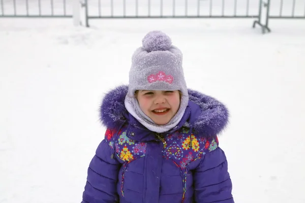 Happy smiling girl in blue jacket and balaclava hat winter day