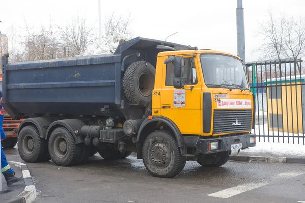 Yellow dump truck MAZ with snow enters into a snow melting point in Moscow