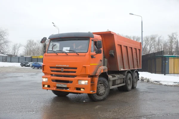 Orange dump truck KAMAZ on snow-melting point, Moscow