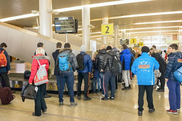 Moscow, Russia - 17 February 2016: Croud waiting at conveyor belt to pick its luggage in arrivals lounge of Sheremetievo airport terminal building.