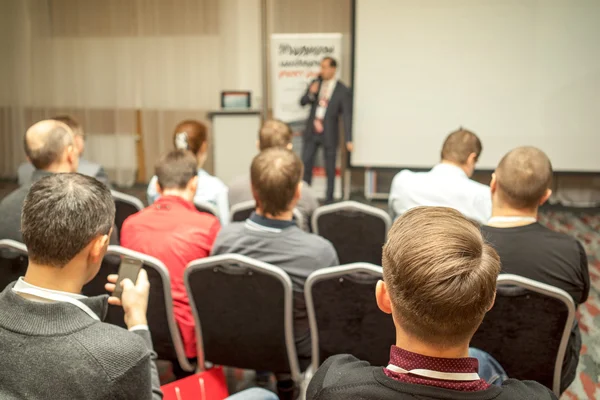 Speaker Giving a Talk at Business Meeting. Audience in the conference hall. Business and Entrepreneurship. Copy space on white board.