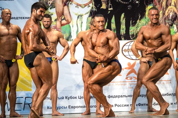 Reutov, Russia - April 02, 2016: men bodybuilders in full growth demonstrates biceps and abdominal muscles during the Cup of Moscow Region on bodybuilding, fitness and bodyfitness.