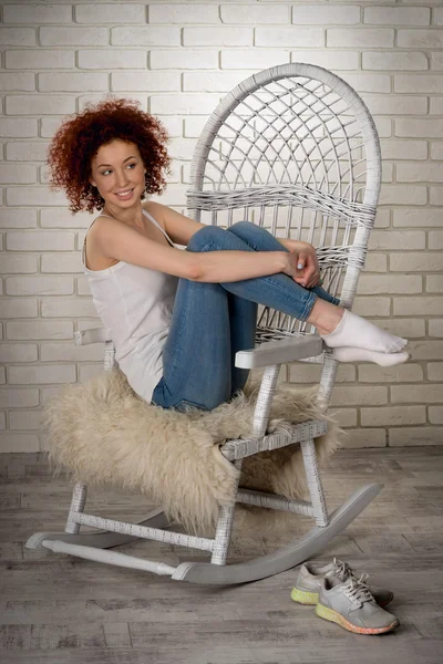 Portrait of a beautiful red-haired young girl on a rocking chair
