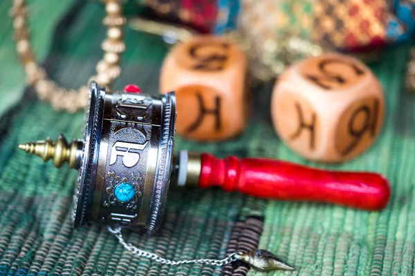 A Tibetan Prayer Wheel to increase good and get rid of bad karma laying on the table with dice