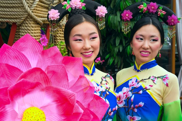 Two chinese women in traditional dresses and lotus floral parasol