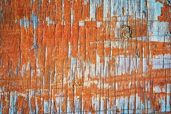 Old wooden flaky orange painted board with lots of notchings, background
