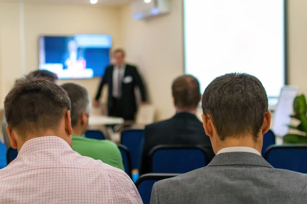 Presenter near the screen and people sitting rear