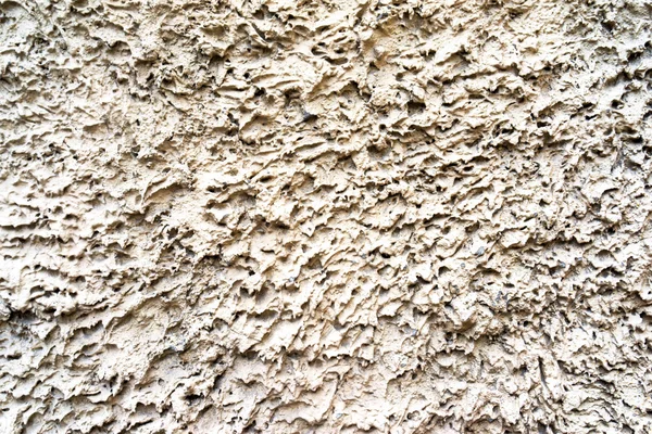 Decorative relief structural light beige plaster on wall closeup