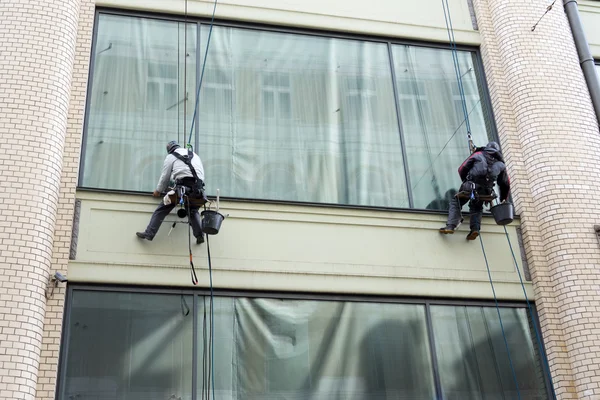 Two men cleaning windows service on high rise building