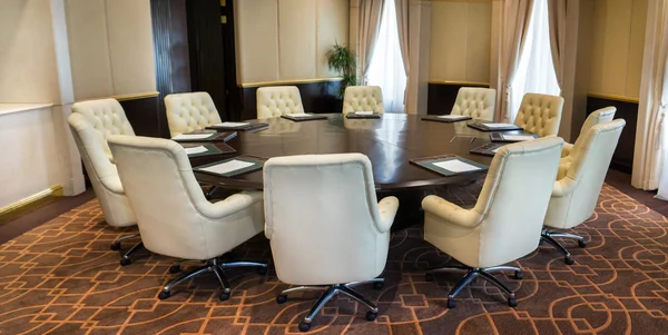 Interior of a boardroom - round table and white leather armchairs