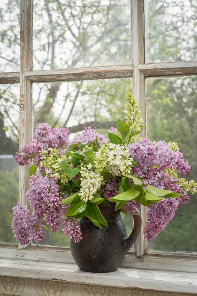 Still life with blooming branche of lilac on a window sill