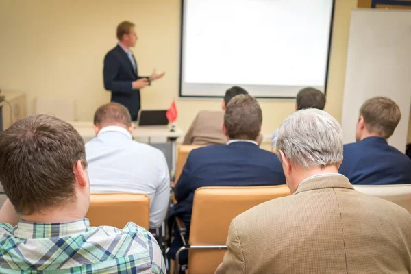 Business Conference and Presentation. Audience at the conference hall. Orator near the white screen,