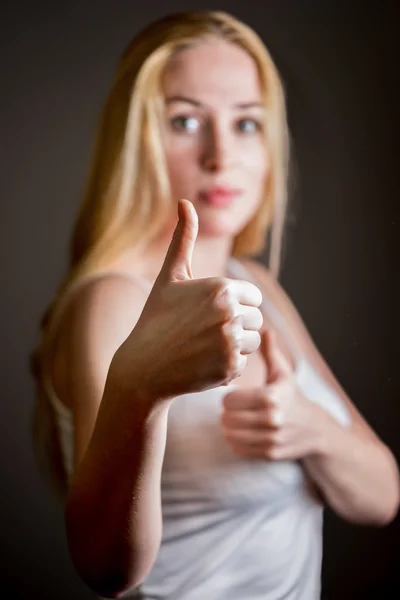 Caucasian woman giving thumb up gesture over gray background.