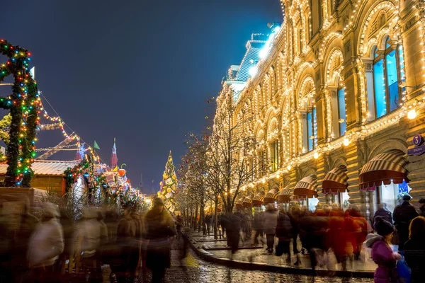 Blurred tourists near illuminated facade of GUM Department store on Red Square during Christmas Fair in Moscow. Red Square is the central historical square in Moscow.