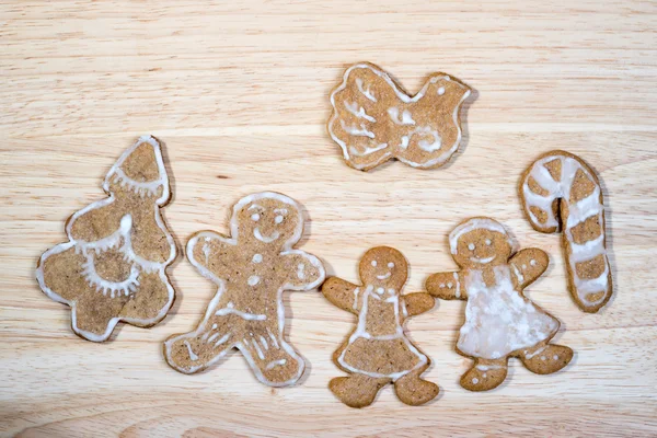 Gingerbread homemade figures of family with christmas tree candy cane and bird on a wooden board