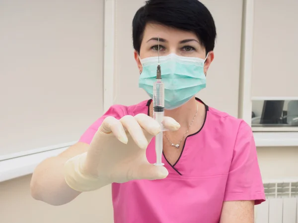 Medical doctor with syringe preparing to make injection