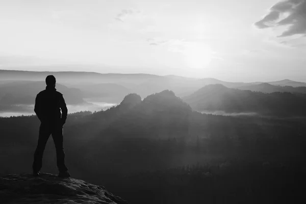Hiker stand on the sharp corner of sandstone rock in rock empires park and watching over the misty and foggy morning valley to Sun. Beautiful moment the miracle of nature