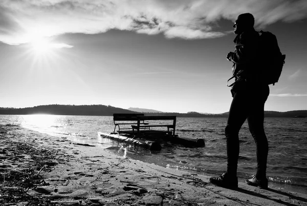 Walk along sea. Man with backpack walk on beach at rusty  pedal boat. Autumn at sea.