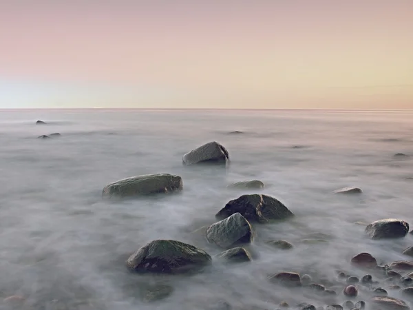 Sunset at rocky coast of sea. Low shutter speed for smooth water level and dreamy effect