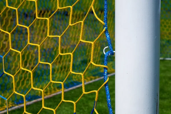 Hang bended blue yellow soccer nets, soccer football net. Plastic grass and white painted line on football play