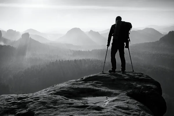 Tourist with leg in immobilizer. Hiker silhouette with medicine crutch on mountain