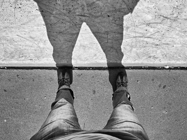 Man long legs stand on street at concrete wall with shadow