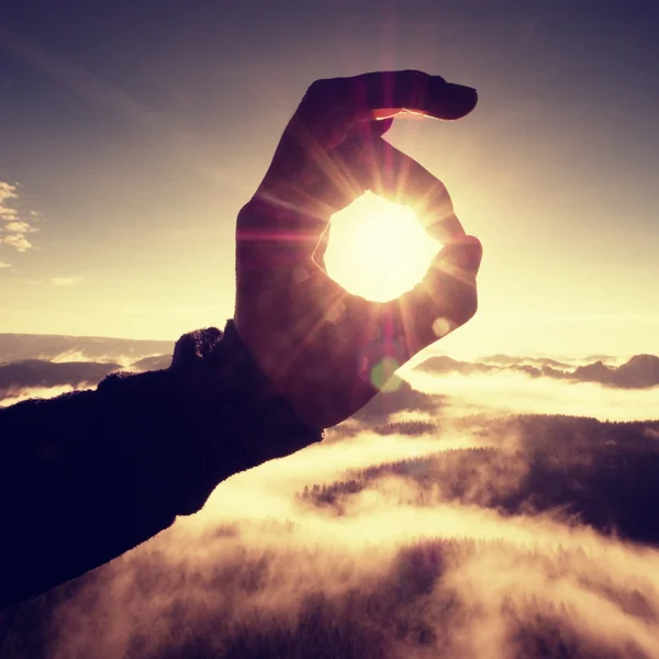 Man hand touch Sun. Misty daybreak in a beautiful hills.