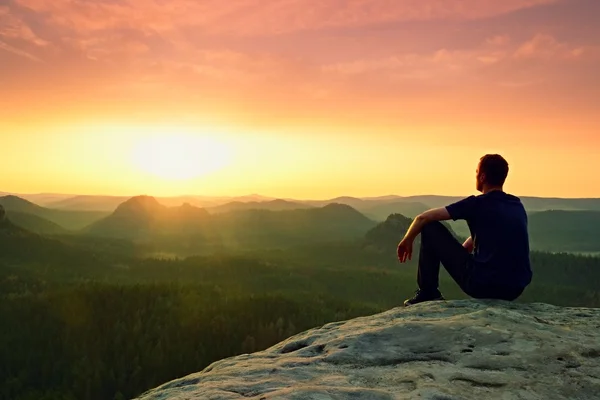 Moment of loneliness. Man sit on rock peak , enjoy daybreak