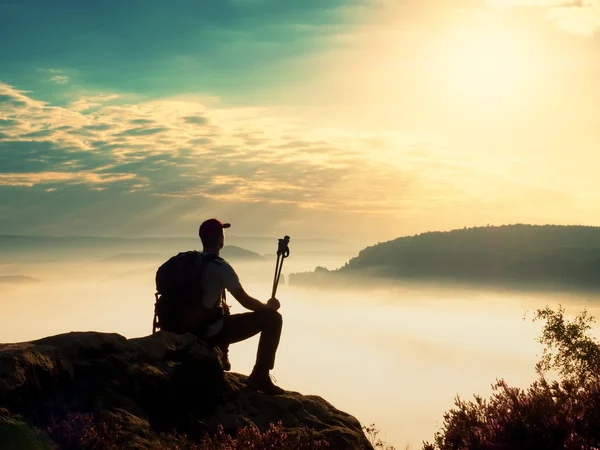 Tall tourist with poles in hand. View point above heavy misty valley.