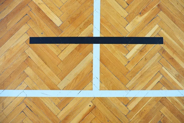 Worn out wooden floor of sports hall with colorful marking lines.