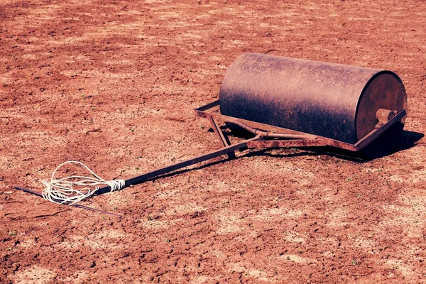 Old rusty iron barrel for maintenance of neglect tennis court. Old dry red crushed bricks surface on outdoor tennis ground. Retro filter