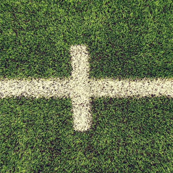 Detail of crossed white lines on outdoor football playground. Detail of lines in a soccer field. Plastic grass and finely ground black rubber.