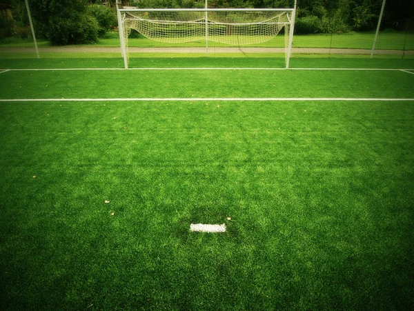 Football playground view of grass field, gate at the end. Detail of a corner in a soccer field. Plastic grass and finely ground black rubber.